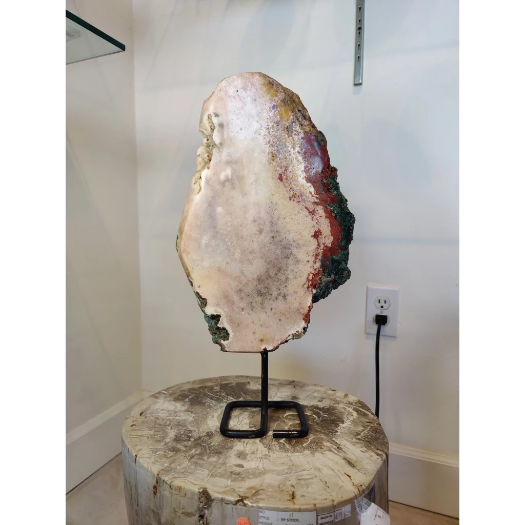 Pink amethyst polished slab sculpture with creamy white interior and vibrant red green and yellow mineral veins on metal stand