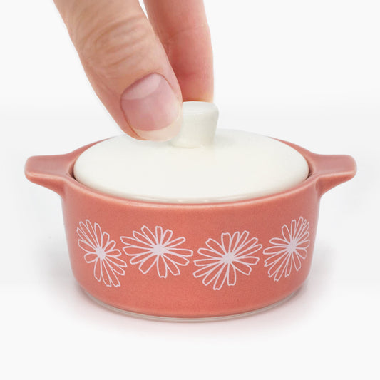 Hand lifting the white lid of the pink Pink Daisy mini casserole trinket box