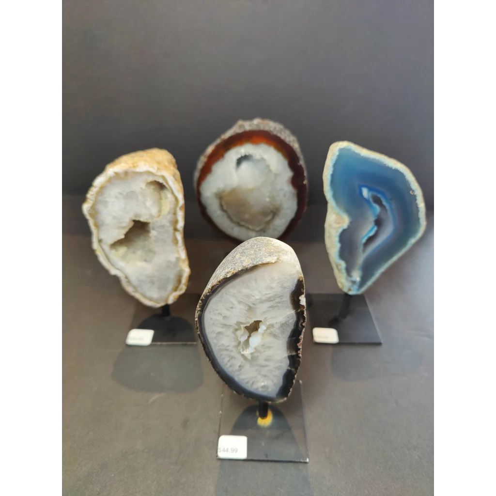 Four polished agate geode specimens with vibrant colors and unique crystals displayed on metal stand