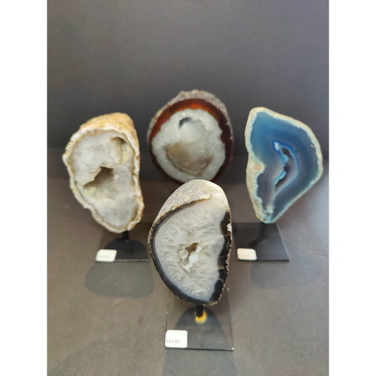 Four polished agate geode specimens with vibrant colors and unique crystals displayed on metal stand