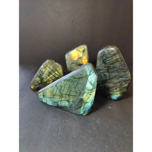 Four polished labradorite stones with iridescent green and gold hues in a polished labradorite free form sculpture