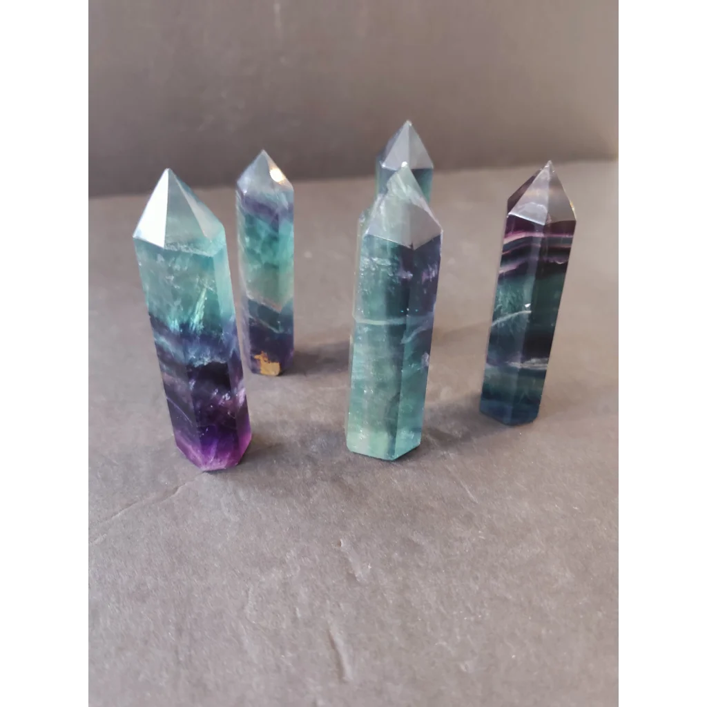 Five polished multi-color fluorite tower points displaying translucent teal and deep purple hues with natural banding patterns