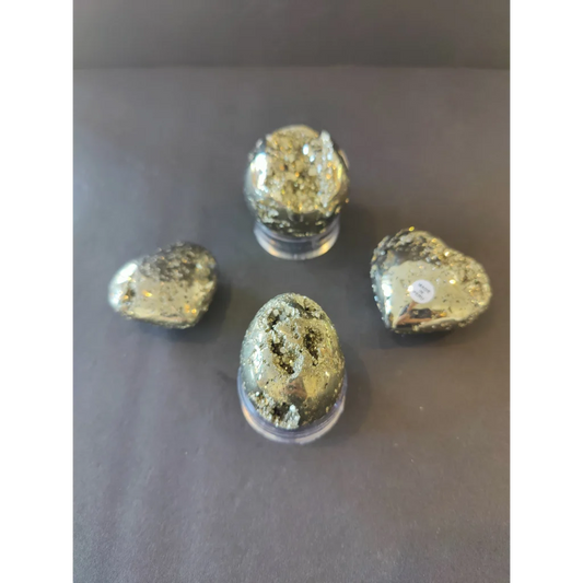 Shiny golden polished pyrite hearts and ovals displayed on clear acrylic stands as polished pyrite spheres and eggs