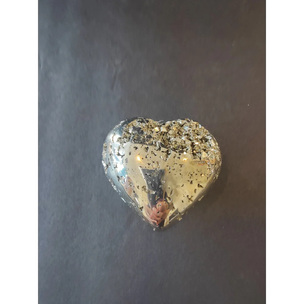A heart-shaped polished pyrite pendant with a reflective metallic surface embedded with golden flecks