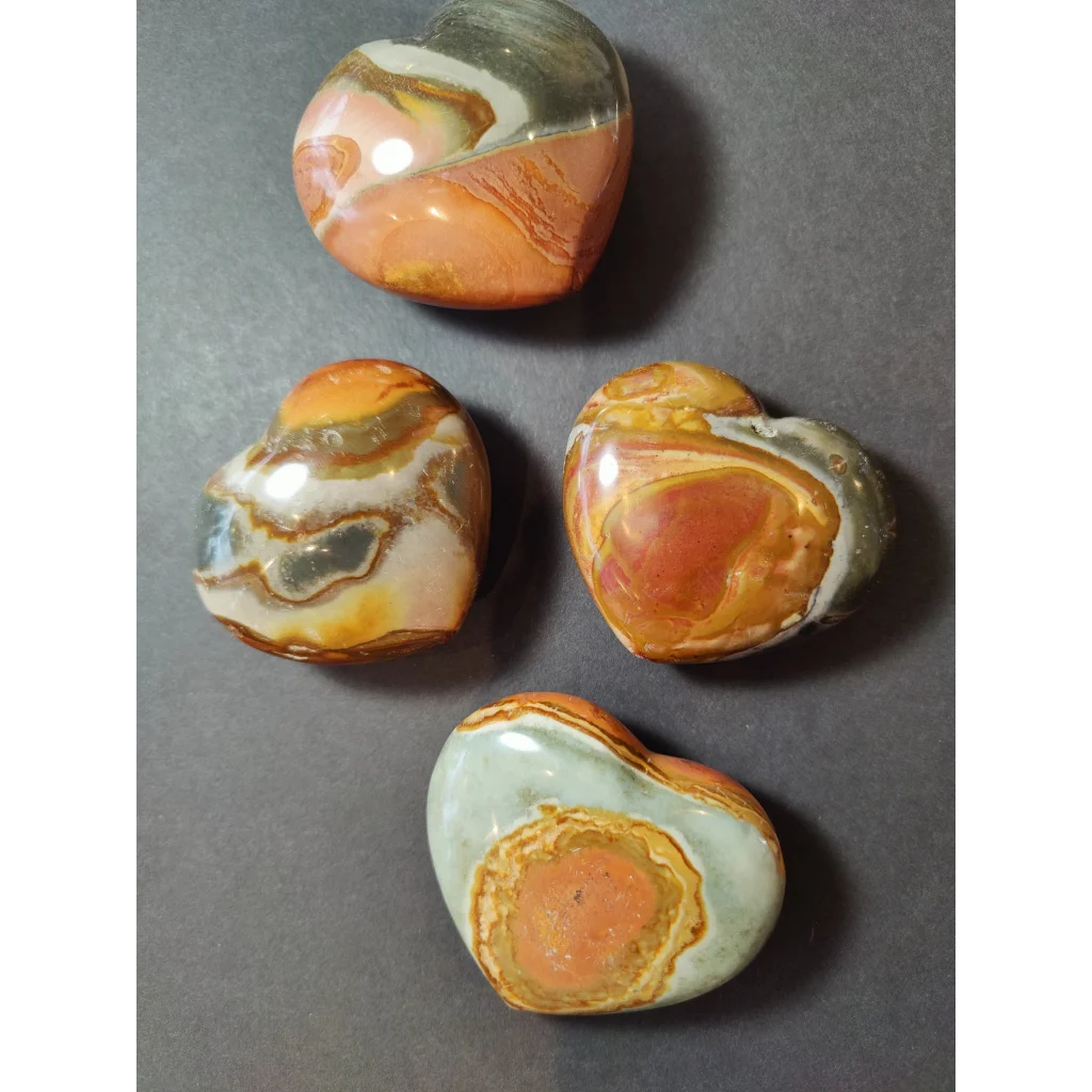 Four polished polychrome jasper carved hearts with swirling orange white and gray patterns