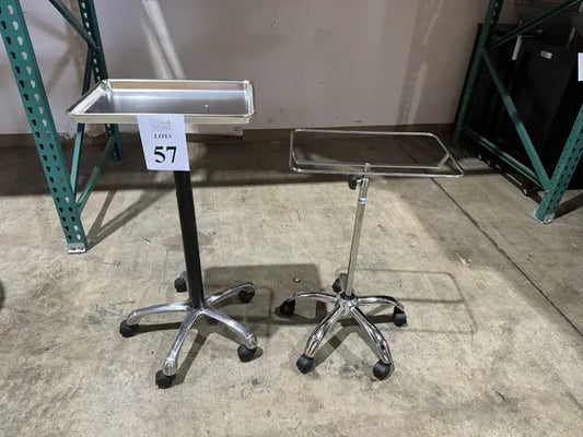 Two stainless steel medical rolling carts with rectangular trays and wheeled bases displayed on concrete floor, lot number 57 visible.