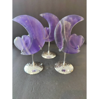 Three translucent purple fluorite half-moon heart sculptures on silver-toned metal stands for decorative display