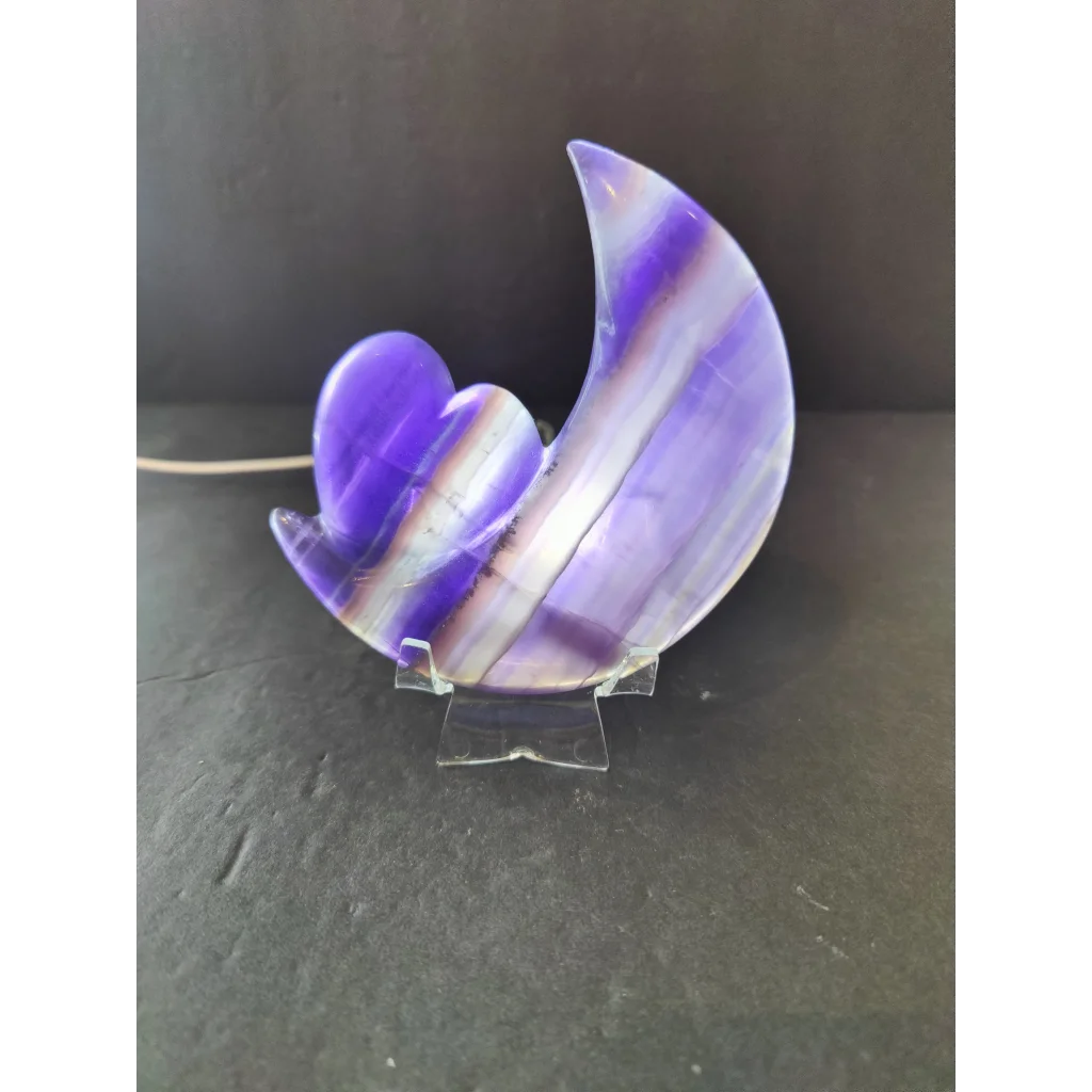 A polished purple fluorite crescent moon and heart sculpture with a smooth surface on a 5 inch metal stand