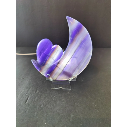 A polished purple fluorite crescent moon and heart sculpture with a smooth surface on a 5 inch metal stand