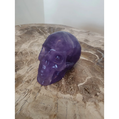 Purple fluorite skull sculpture featuring a translucent purple amethyst skull with polished surfaces and natural inclusions