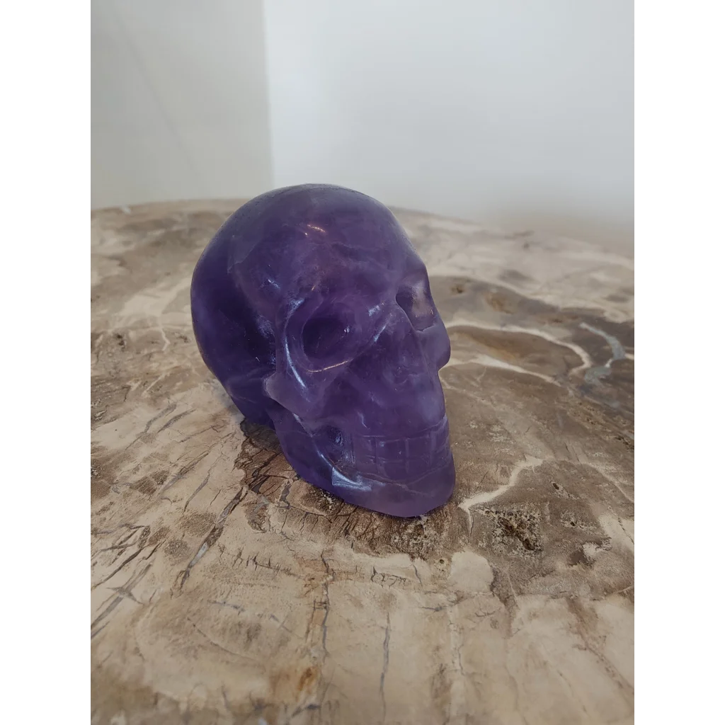 Translucent purple fluorite skull sculpture with smooth polished surfaces and detailed facial features