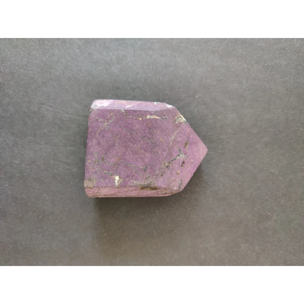Purpurite lapidary: faceted purple crystal with inclusions, pointed shape