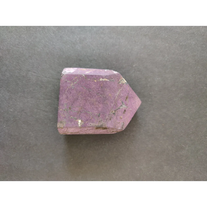 Purpurite lapidary: faceted purple crystal with inclusions, pointed shape