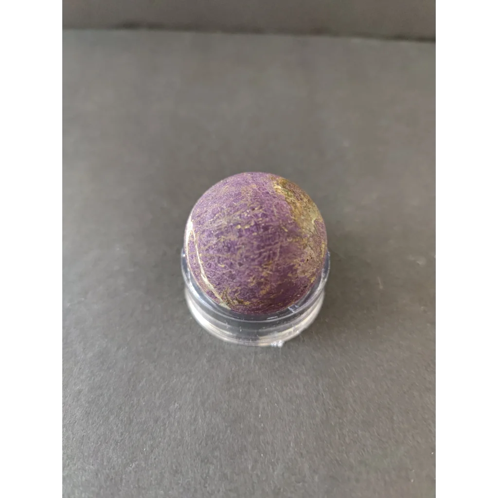 Polished purpurite lapidary sphere in purple gold speckles on acrylic stand