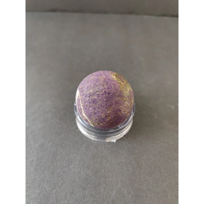 Polished purpurite lapidary sphere in purple gold speckles on acrylic stand