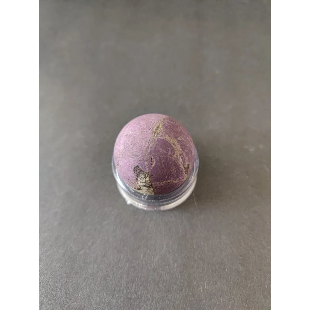 Purpurite lapidary: smooth round purple gemstone with veining in clear stand