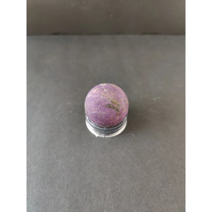 Purpurite Lapidary purple gemstone with golden inclusions on acrylic stand