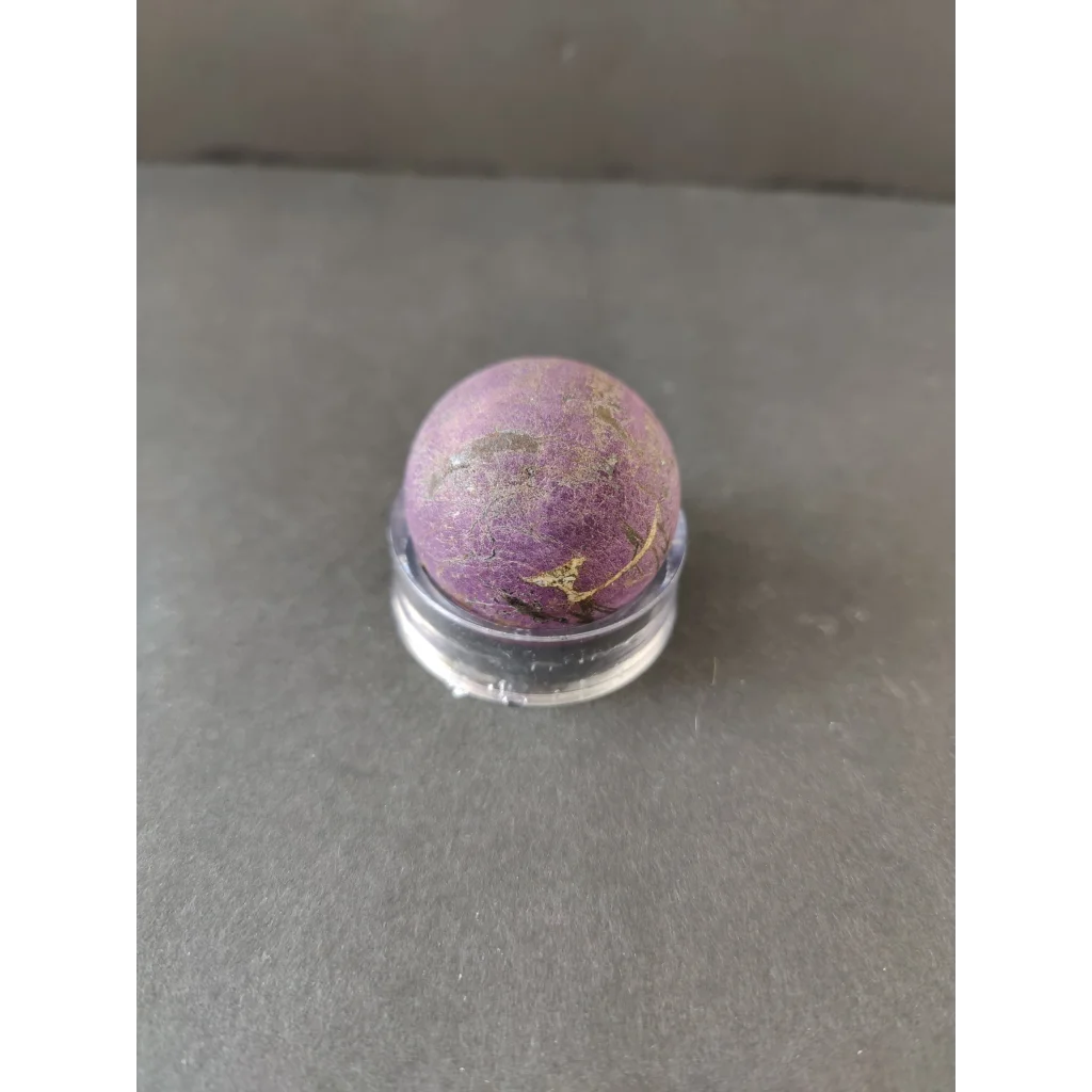 Purpurite Lapidary: smooth round purple stone with golden streaks in display stand