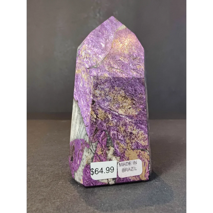 Purpurite polished obelisk tower sculpture in purple and gold displayed on a stand with a pointed top