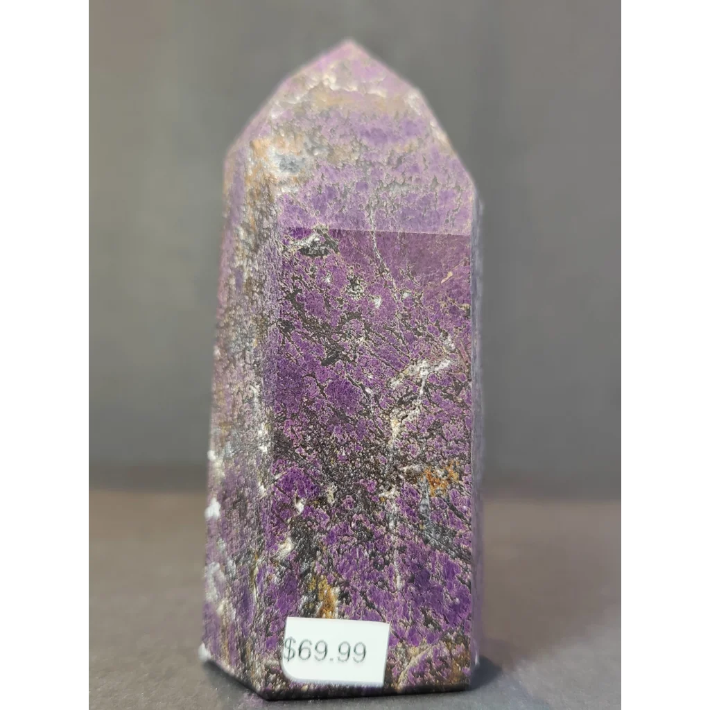 A polished purple purpurite polished obelisk tower sculpture with natural banding and metallic inclusions standing upright
