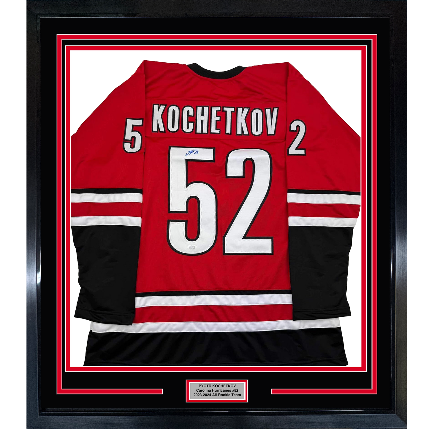 Framed red Carolina Hurricanes hockey jersey number 52 with "Kochetkov" nameplate, displayed flat against white background with black and red border matting.
