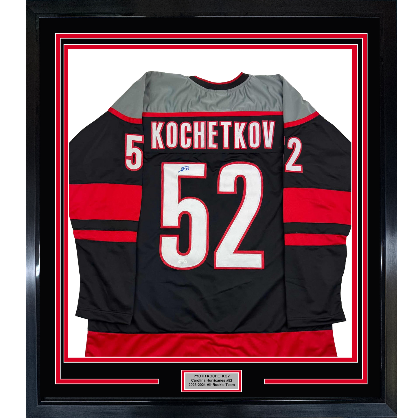 Framed black Carolina Hurricanes hockey jersey #52 with red stripes, displaying "KOCHETKOV" and number, mounted behind glass with red and white matting.