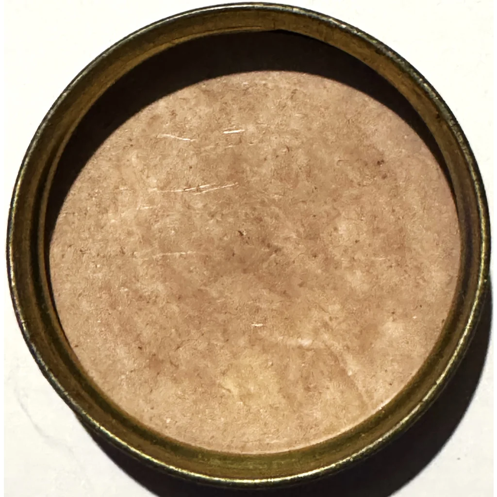 Circular cream tin lid filled with light brown granules from the 1800s collectible