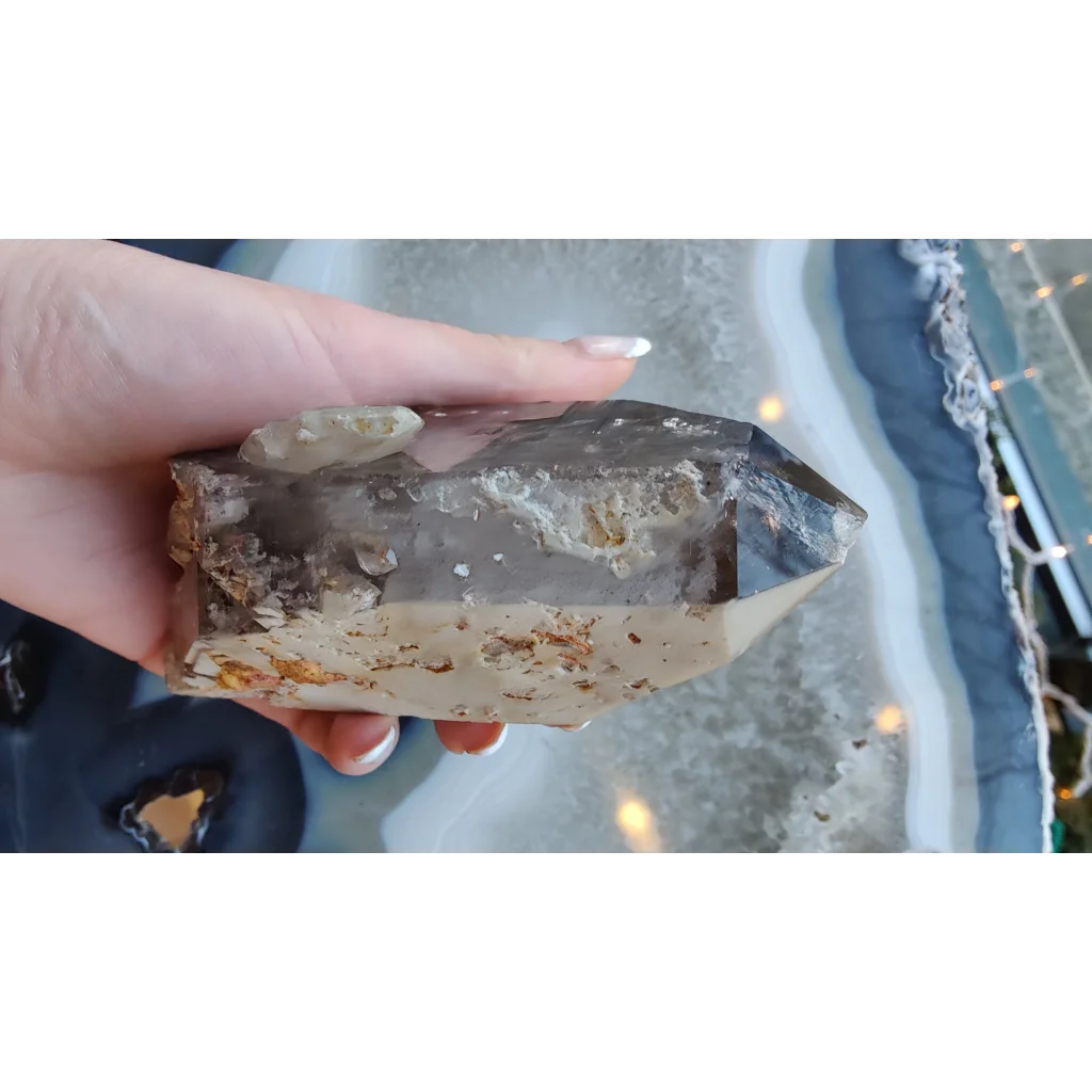 Hand holding rare Brazilian smokey quartz point with lodalite inclusions
