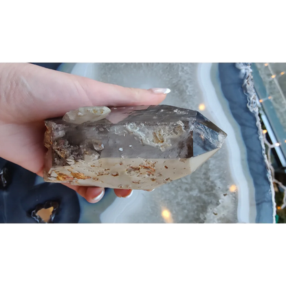 Hand holding rare Brazilian smokey quartz point with lodalite inclusions