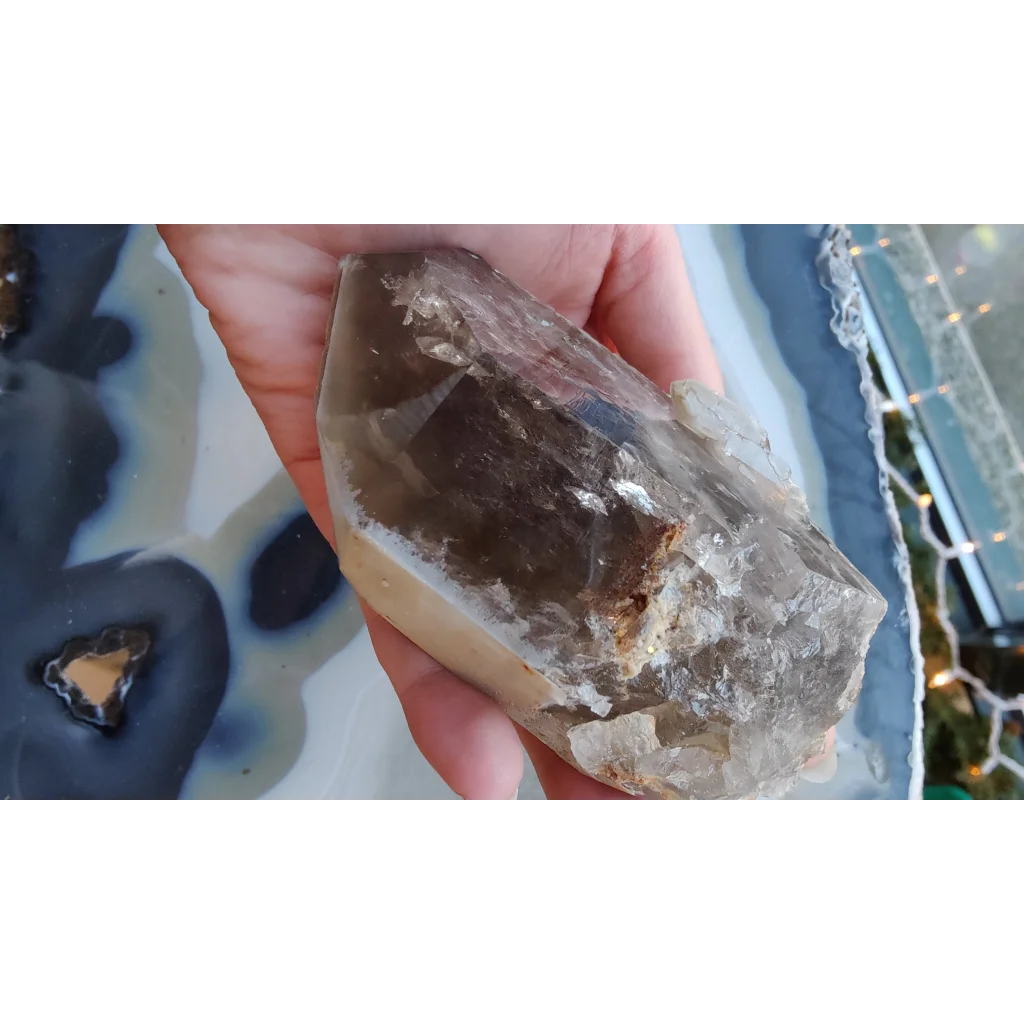Hand holding rare Brazilian smokey quartz point with lodalite inclusions