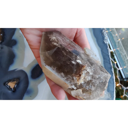 Hand holding rare Brazilian smokey quartz point with lodalite inclusions