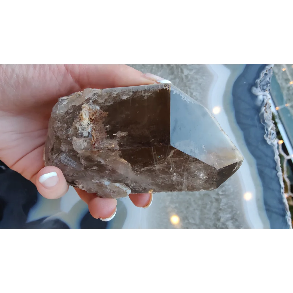 Hand holding rare Brazilian smokey quartz point with lodalite inclusions