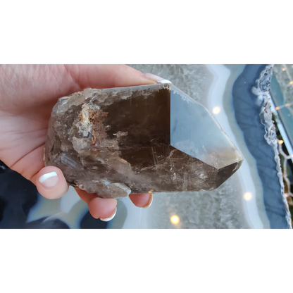 Hand holding rare Brazilian smokey quartz point with lodalite inclusions