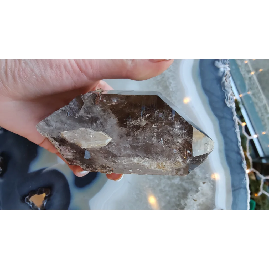 Hand holding rare Brazilian smokey quartz point with lodalite inclusions
