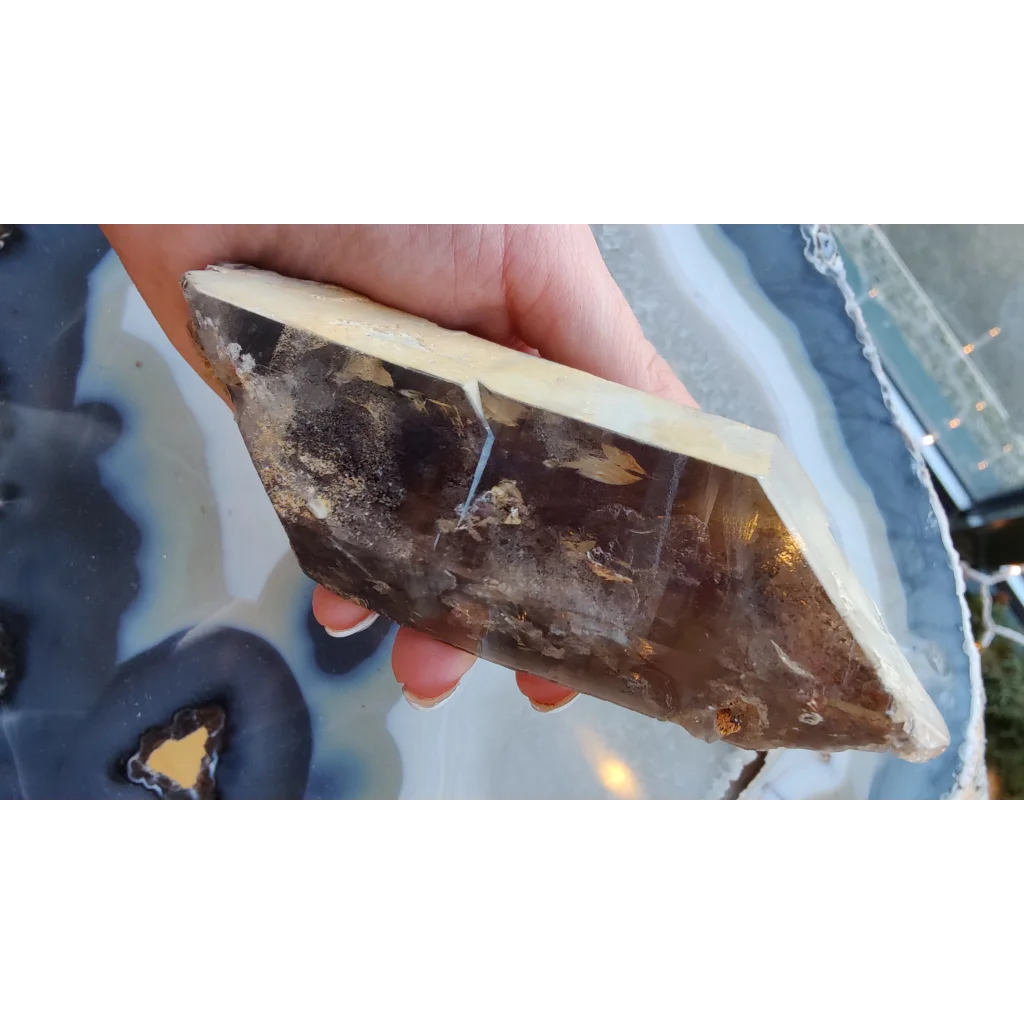 Hand holding rare Brazilian smokey quartz point with lodalite inclusions