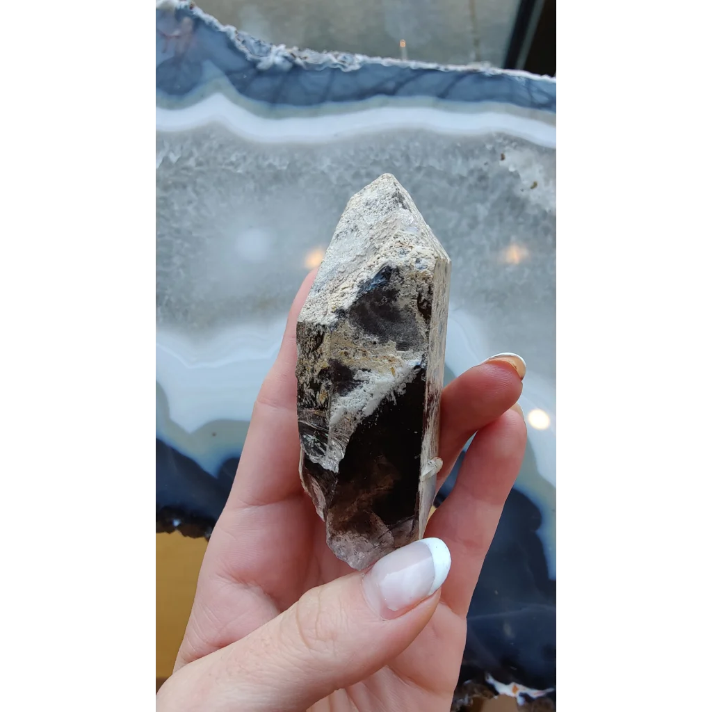Hand holding rare Brazilian smokey quartz point with lodalite inclusions