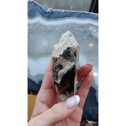 Hand holding rare Brazilian smokey quartz point with lodalite inclusions