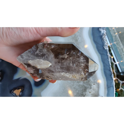 Hand holding rare Brazilian smokey quartz point with lodalite inclusions