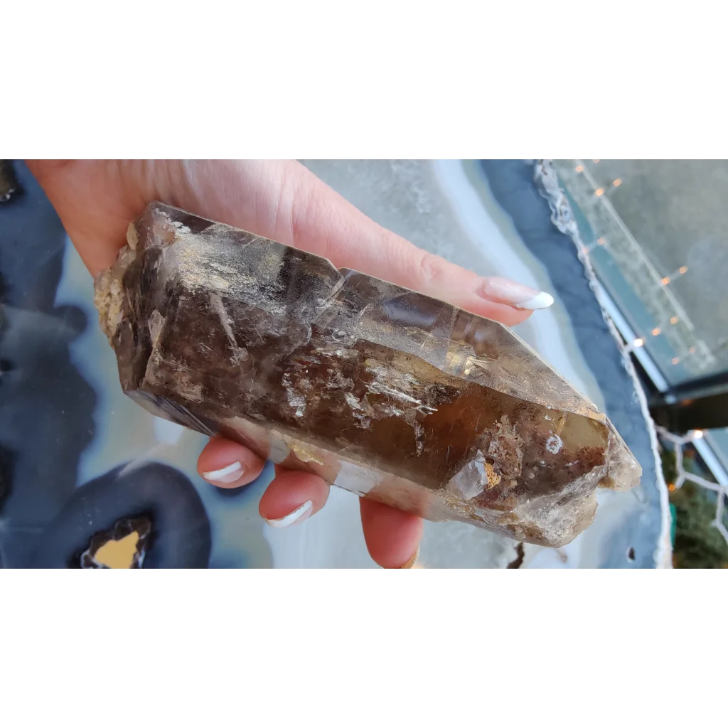 Hand holding rare Brazilian smokey quartz point with lodalite inclusions
