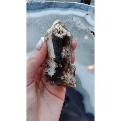 Hand holding rare Brazilian smokey quartz point with lodalite inclusions
