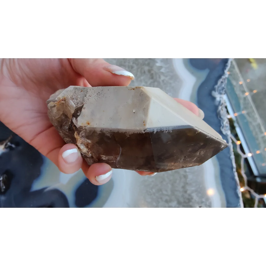 Hand holding rare Brazilian smokey quartz point with lodalite inclusions