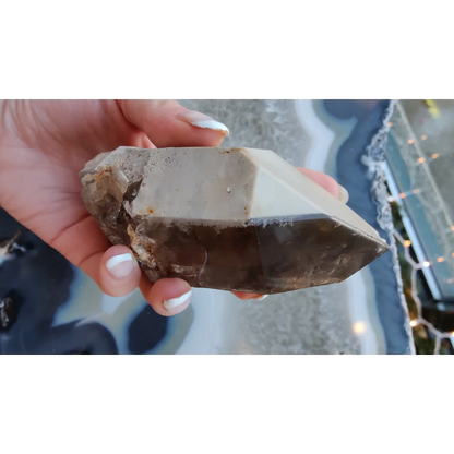 Hand holding rare Brazilian smokey quartz point with lodalite inclusions