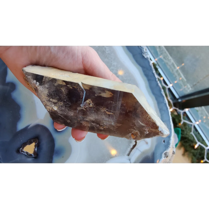Hand holding rare Brazilian smokey quartz point with lodalite inclusions