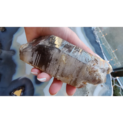 Hand holding rare Brazilian smokey quartz point with lodalite inclusions