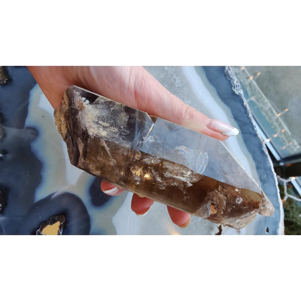 Hand holding rare Brazilian smokey quartz point with lodalite inclusions