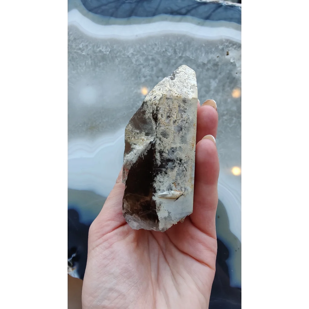 Hand holding rare Brazilian smokey quartz point with lodalite inclusions