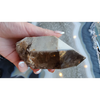 Hand holding rare Brazilian smokey quartz point with lodalite inclusions