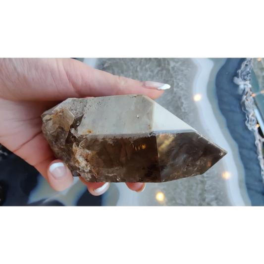 Hand holding rare Brazilian smokey quartz point with lodalite inclusions