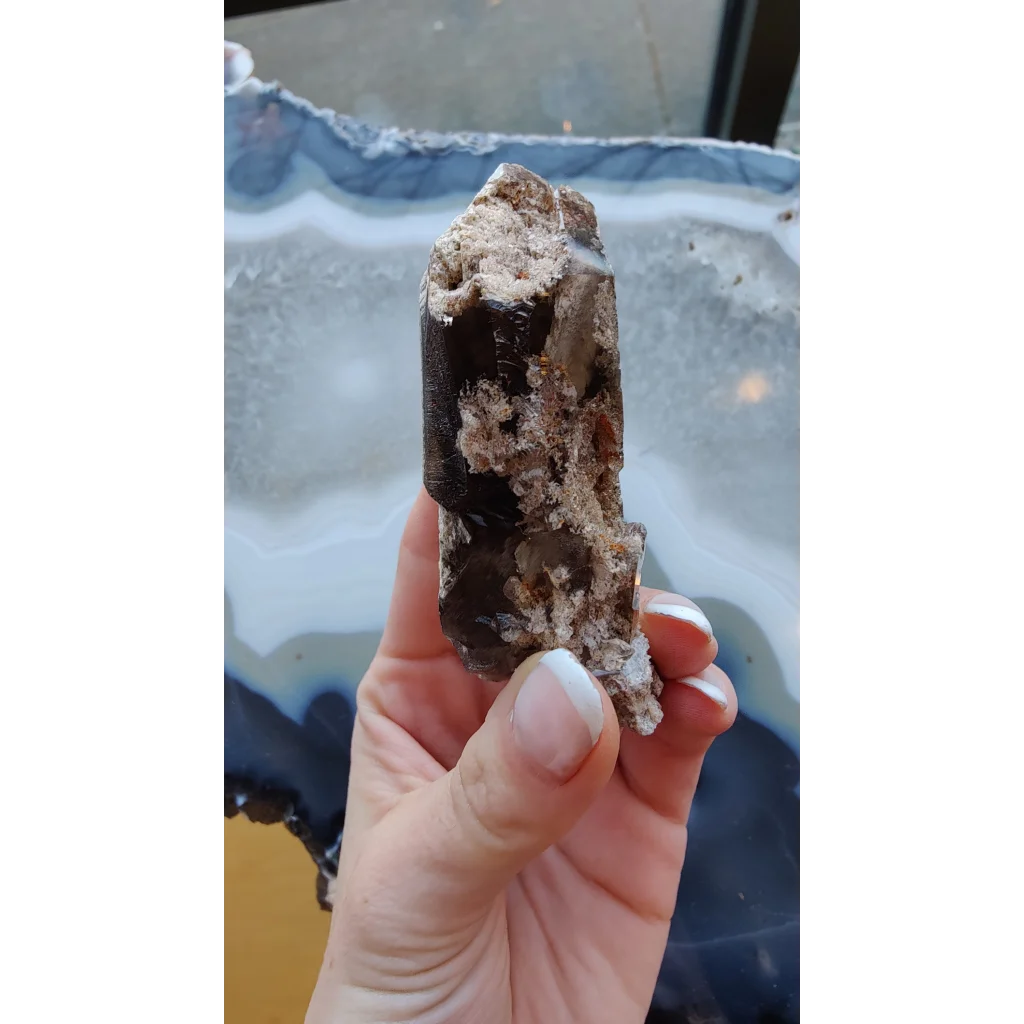 Hand holding rare Brazilian smokey quartz point with lodalite inclusions