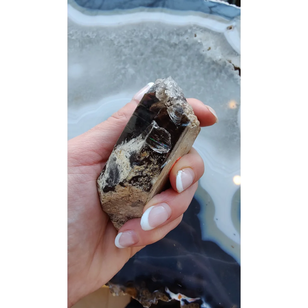 Hand holding rare Brazilian smokey quartz point with lodalite inclusions
